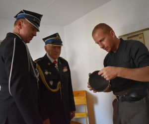 Osoby wewnątrz izby pamięci przeglądają eksponaty.