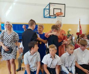 Uczniowie klasy ósmej wręczają róże swoim rodzicom