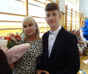 Uczeń klasy ósmej wręcza bukiet kwiatów wychowawczyni z klas młodszych
