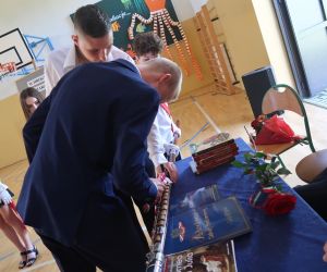 Uczniowie wbijają pamiątkowy gwóźdź w drzewiec sztandaru szkoły