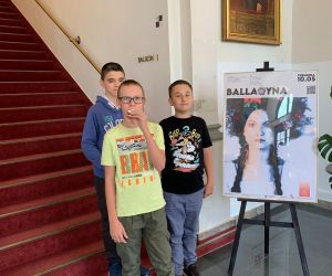 Uczniowie stojący przy plakacie zapowiadającym sztukę „Balladyna”