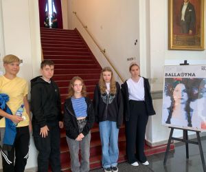 Grupa uczniów przy plakacie teatralnym na tle schodów