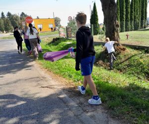 Grupa uczniów zbiera śmieci przy szosie