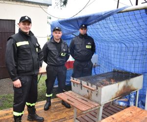 Na zdjęciu znajduje się trzech strażaków z OSP stojących przy grillu.