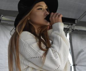 Zdjęcie przedstawia osobę śpiewająca na scenie.