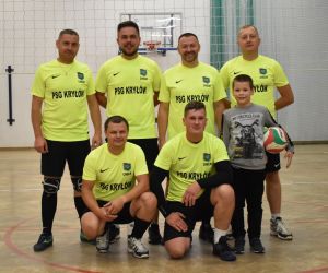 Zdjęcie przedstawia zwycięską drużynę w meczu piłki siatkowej. Na zdjęciu znajduje się 6 dorosłych mężczyzn oraz dziecko trzymające piłkę.