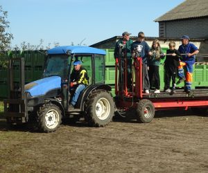 Dwóch uczniów, dwie uczennice i dwaj robotnicy na platformie służącej do zbioru owoców