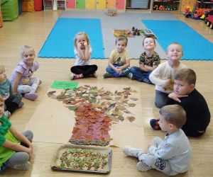 Przedszkolaki wokół wyklejonego plakatu z drzewem