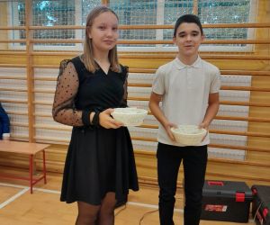 Uczennica i uczeń klasy szóstej z symbolicznymi prezentami dla nauczycieli