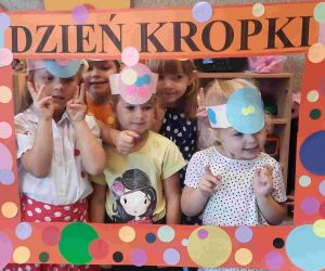 Cztery dziewczynki i chłopiec w strojach w kropki pozują w kropkowanej ramie okolicznościowej