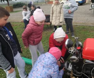 Uczniowie uczą się podłączenia węża do motopompy strażackiej