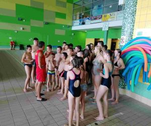 Pomieszczenie pływalni w Chełmie. Uczniowie w strojach kąpielowych słuchają wyjaśnień ratownika.