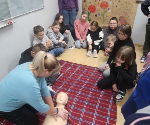 Pani pokazuje dzieciom zasady udzielenia pierwszej pomocy za pomocą fantoma