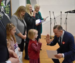 Grupa osób na scenie wewnątrz budynku. Odbiór statuetek, laureaci Konkursu.